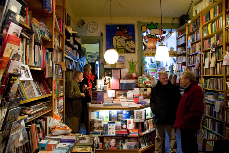 Interieur van boekhandel Schimmelpennink  <p>Klanten in boekhandel Schimmelpennink aan de Weteringschans. Achter de toonbank, met rode sjaal, eigenaar Ton Schimmelpennink.</p>