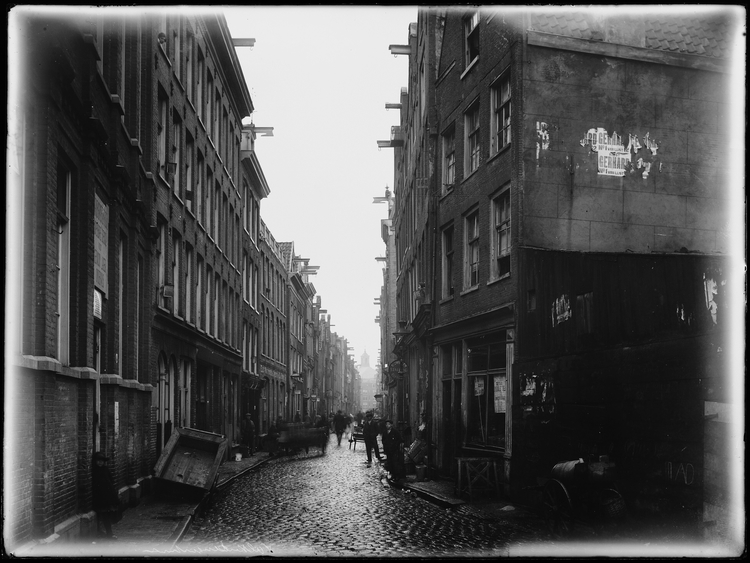 Valkenburgerstraat straatbeeld, door de hele straat handkarren, rechts een zaak voor stalling en reparatie van rijwielen. Beeldbank SAA, december 1926  